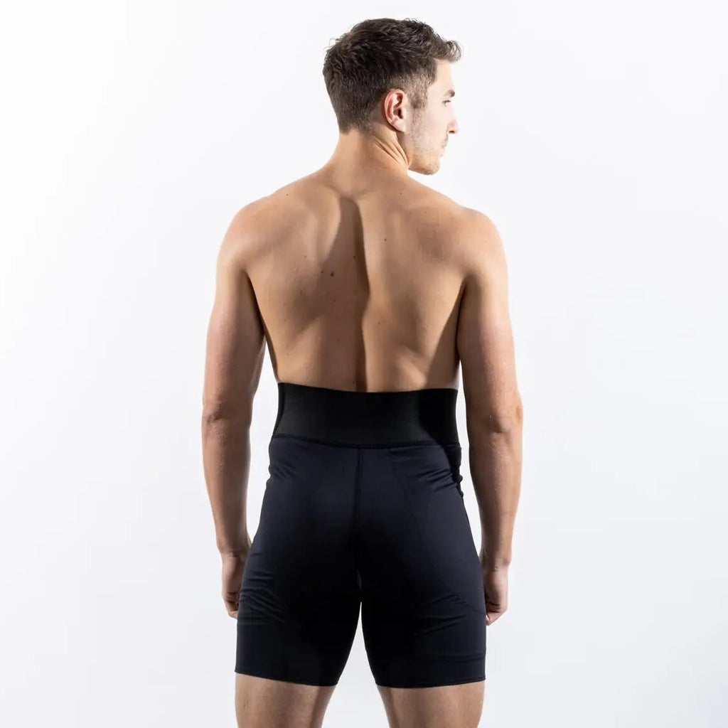 A man viewed from behind wearing black athletic compression shorts against a clean white studio background.