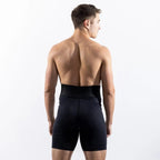 A man viewed from behind wearing black athletic compression shorts against a clean white studio background.