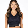 A woman modeling a black sleeveless zip-up vest with a V-neck and ribbed hem, paired with dark blue jeans, against a plain white background.