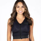 A woman modeling a black sleeveless zip-up vest with a V-neck and ribbed hem, paired with dark blue jeans, against a plain white background.