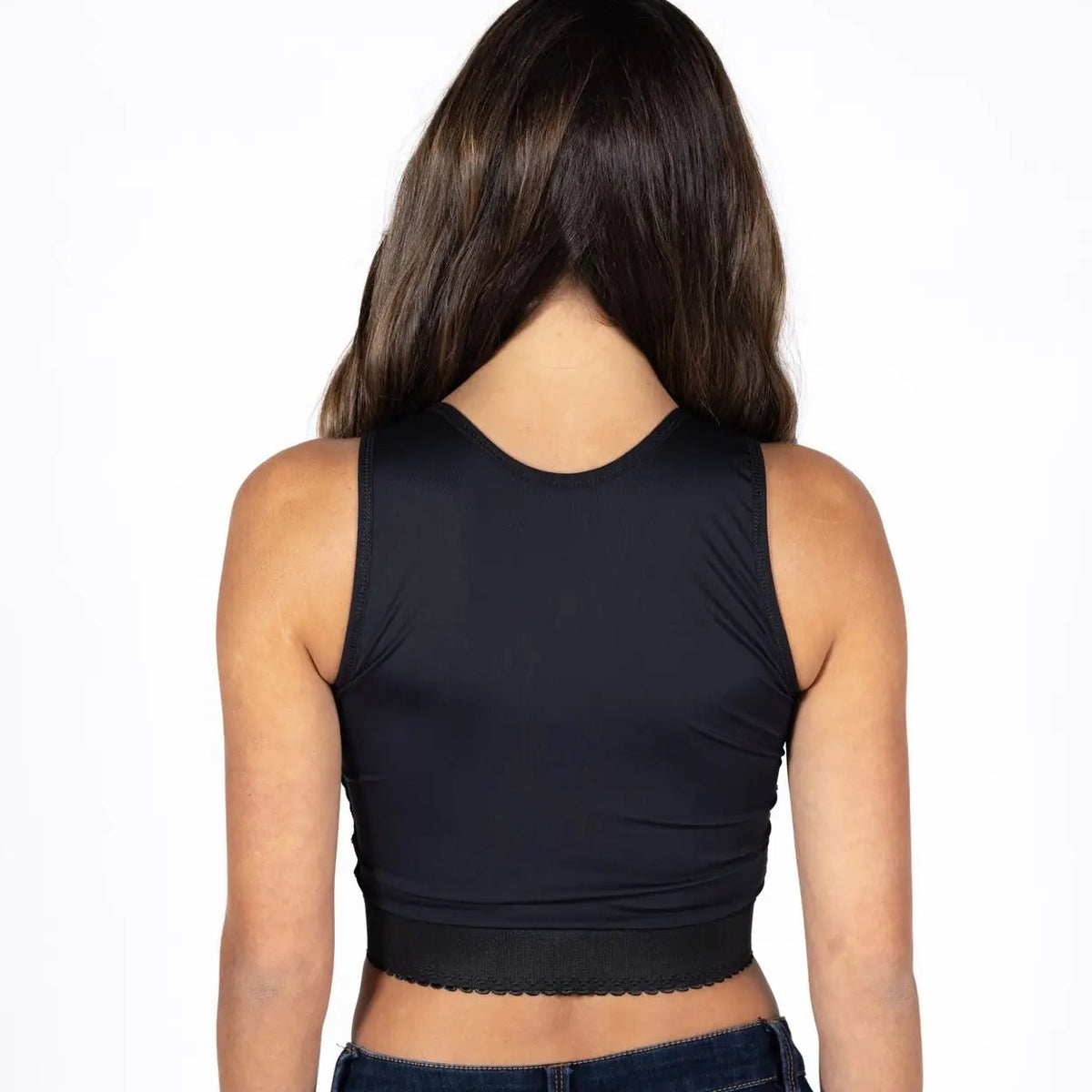 A woman viewed from the back wearing a black sleeveless crop top and dark blue jeans against a plain white background.