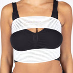 A woman wearing a black and white strappy crop top with wide horizontal white bands and a black sweetheart neckline, paired with dark blue jeans.