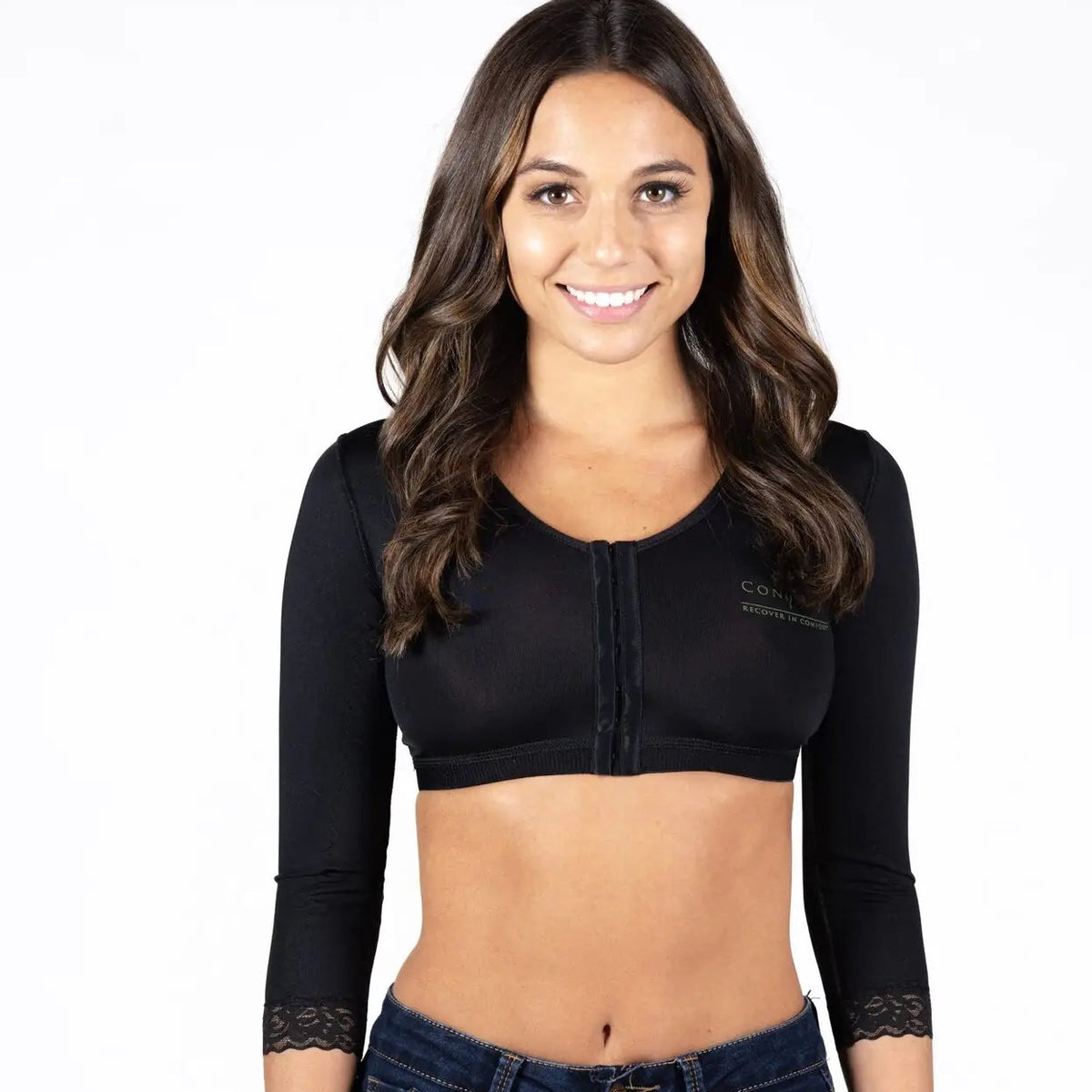 A woman modeling a black three-quarter sleeve crop top with a front zipper and lace cuffs, paired with dark blue jeans, against a plain white background.