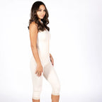 A woman modeling a light beige compression or shapewear bodysuit with capri-length legs, shown in profile against a plain white studio background.