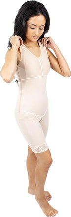 A woman modeling a light beige compression shapewear bodysuit with mid-thigh legs and lace trim at the hem, set against a plain white background.