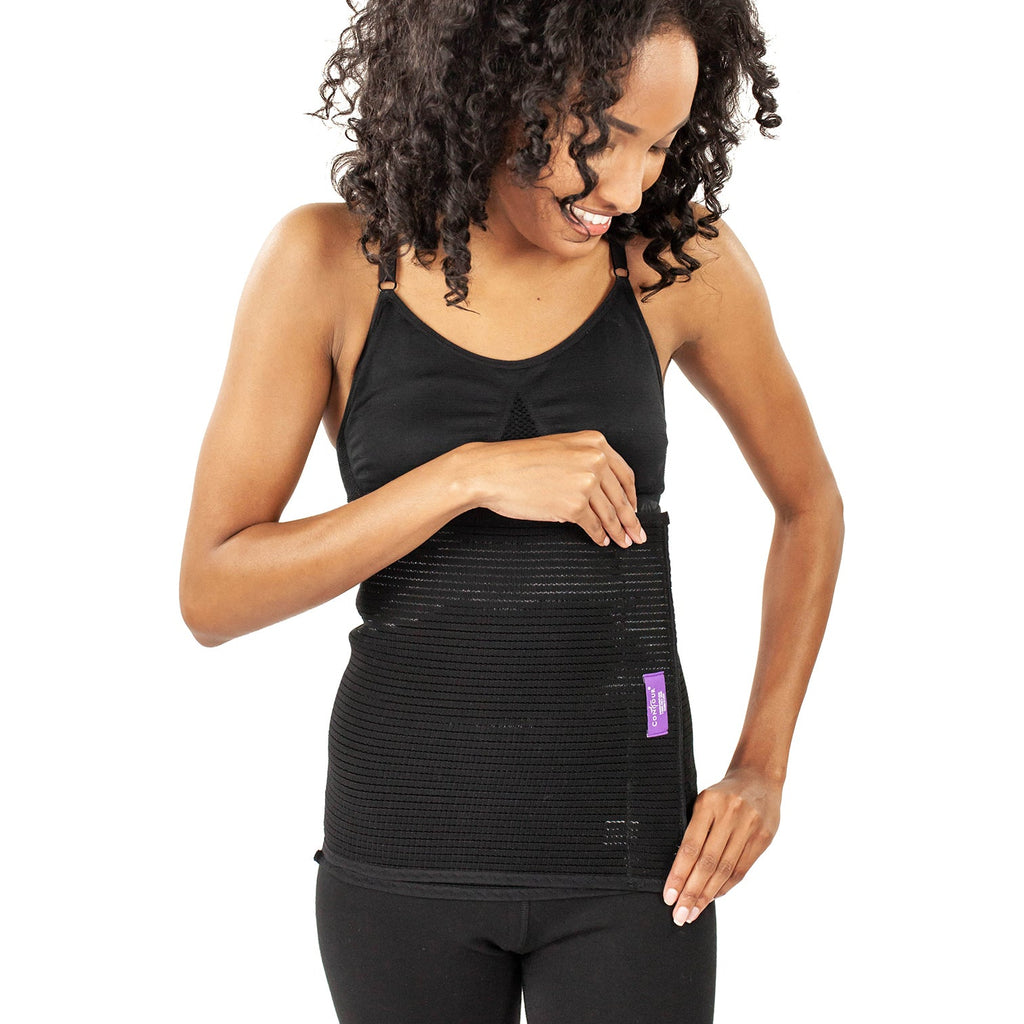 A woman with curly black hair wearing a black ribbed athletic tank top and matching black leggings, shown against a plain white background.